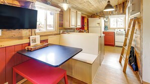 Une cuisine compacte avec des meubles en bois, une cuisinière encastrée et un coin repas comprenant un banc et une table.
