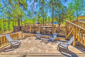 A deck with Adirondack chairs, a stone patio, and a wooden fence. - Relaxing Ruidoso Getaway w/ Spacious Deck! (Ruidoso)