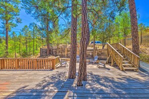 A wooden deck with a staircase leading to a covered area, surrounded by pine trees. - Relaxing Ruidoso Getaway w/ Spacious Deck! (Ruidoso)