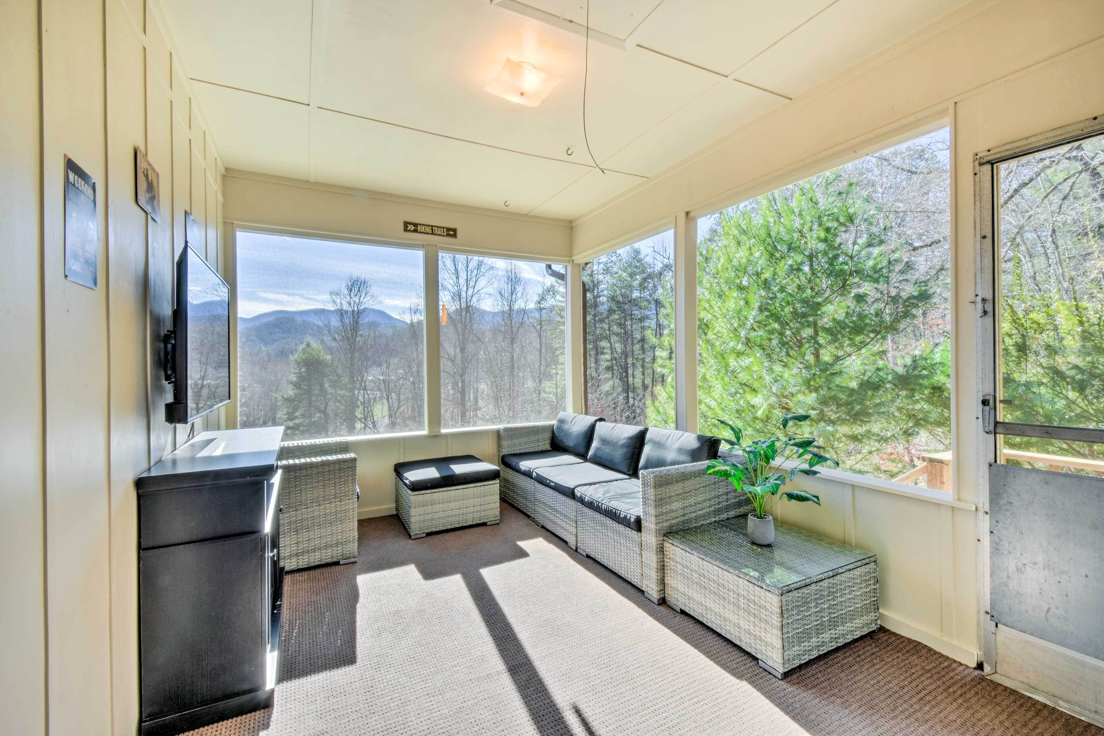 A sunroom with a sofa, a small table, and a potted plant.