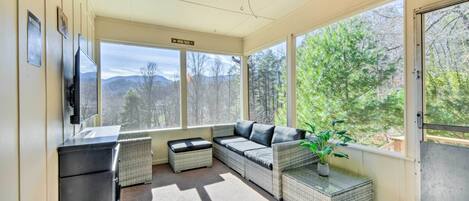 A sunroom with a sofa, a small table, and a potted plant.