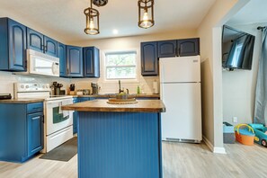 Une cuisine moderne avec des meubles bleus, des appareils électroménagers blancs et un îlot central.