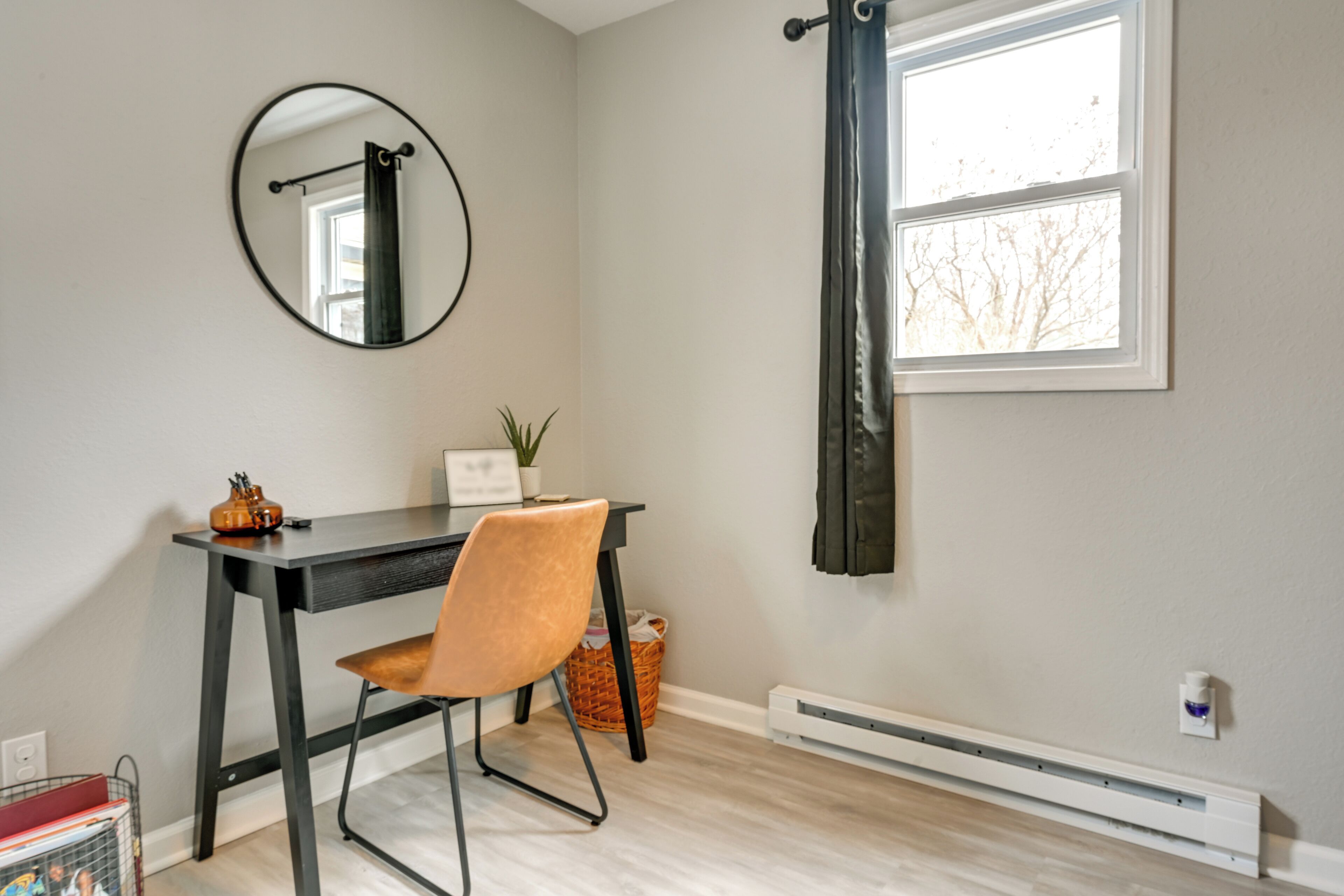 Une pièce comprenant un bureau, une chaise et un grand miroir au mur.