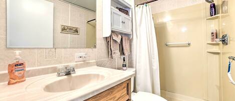 A bathroom with a sink, mirror, toilet, and shower.