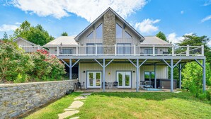Une maison à deux étages avec une façade en pierre, un balcon doté d’une balustrade et un mur de pierre sur le côté gauche.