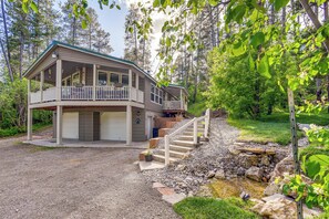 A two-story house with a covered porch, a front garage, and a stone staircase leading to a small pond.