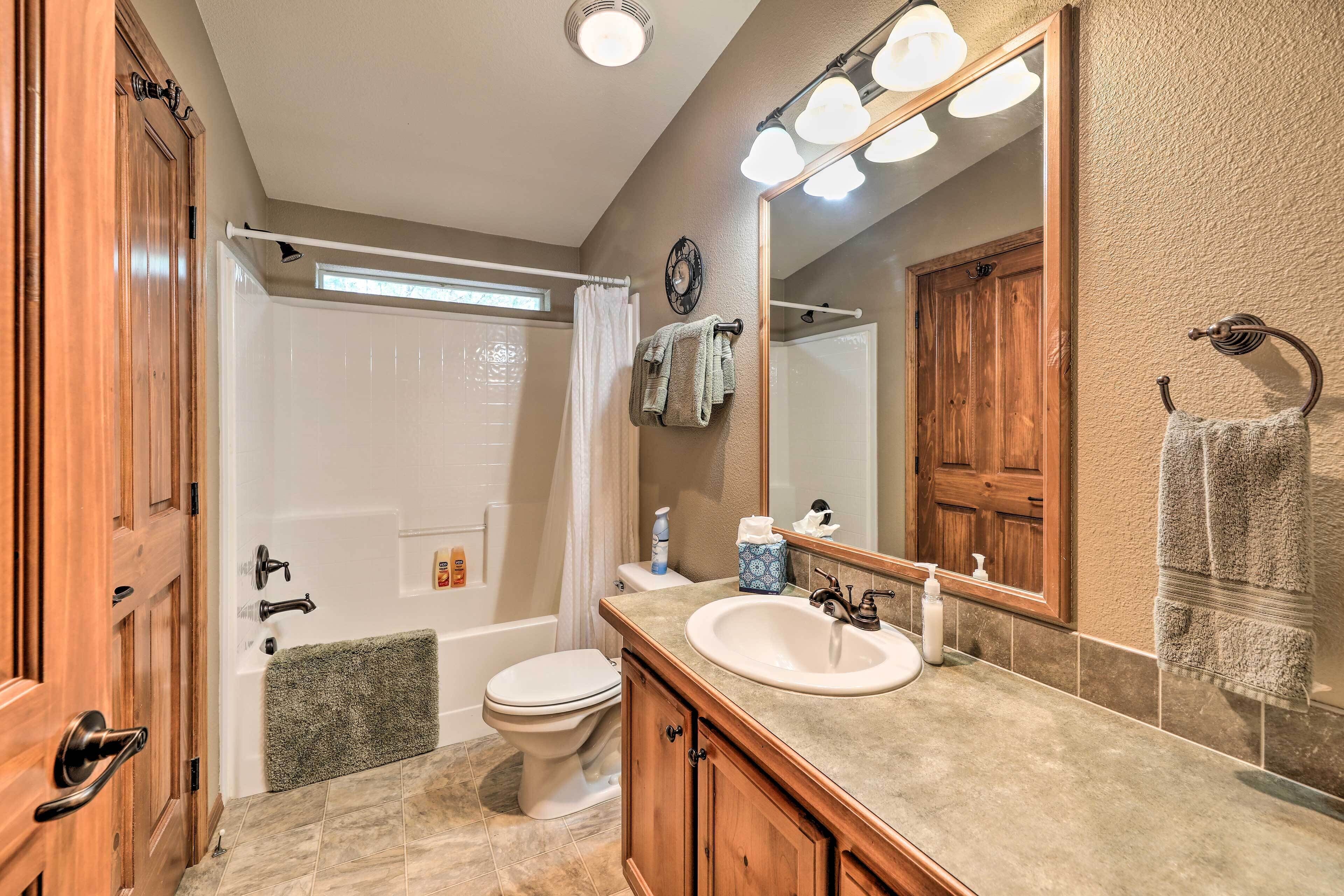 A bathroom with a bathtub, toilet, sink, and vanity.
