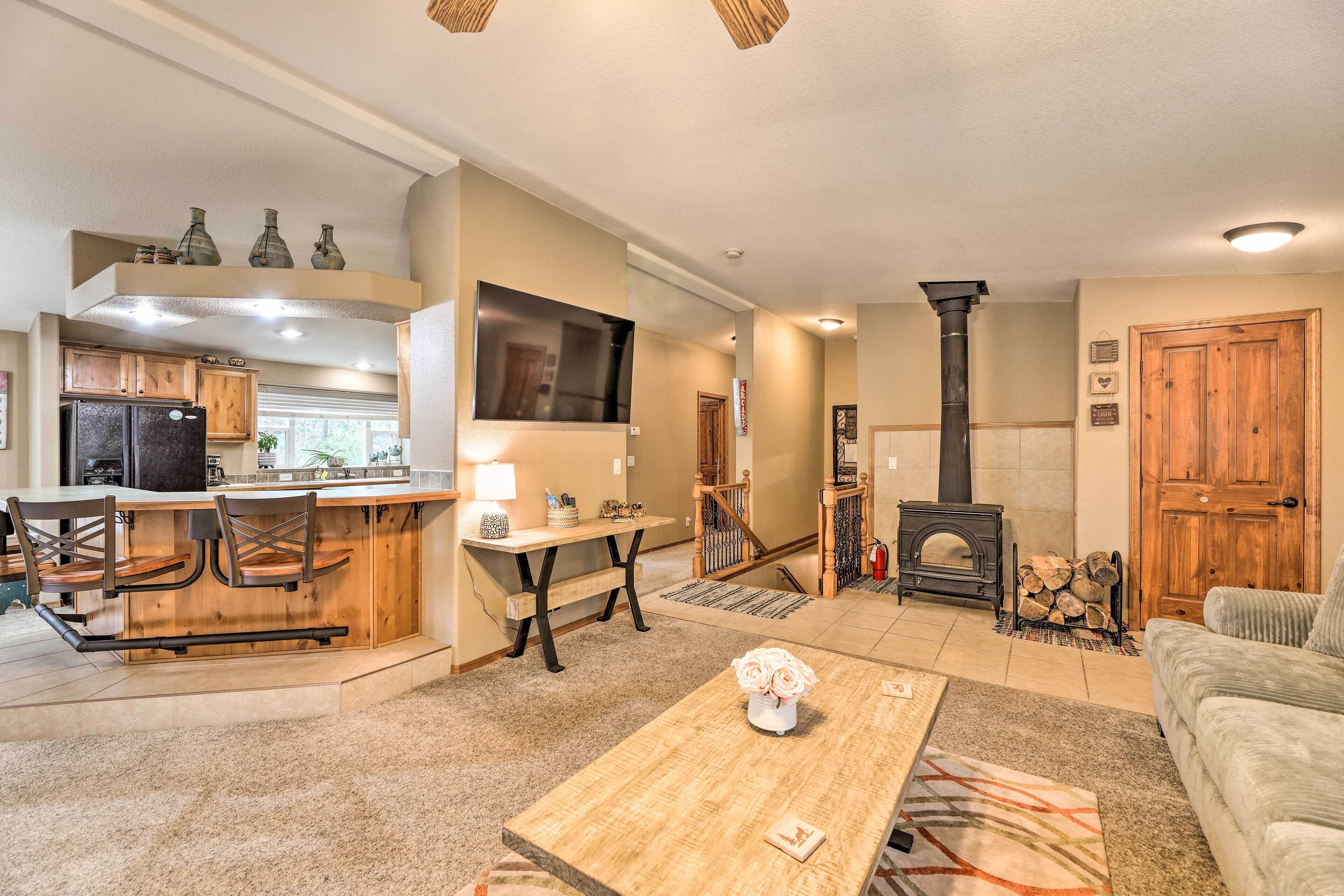 Una sala de estar moderna con chimenea, un comedor con mesa y sillas de madera, y una cocina con refrigerador y armarios.