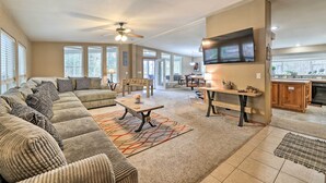 A spacious living room with a sectional sofa, a dining table, and a kitchen area visible in the background.