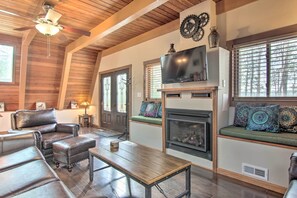 Un amplio salón con chimenea, muebles de cuero y un televisor montado en la pared.