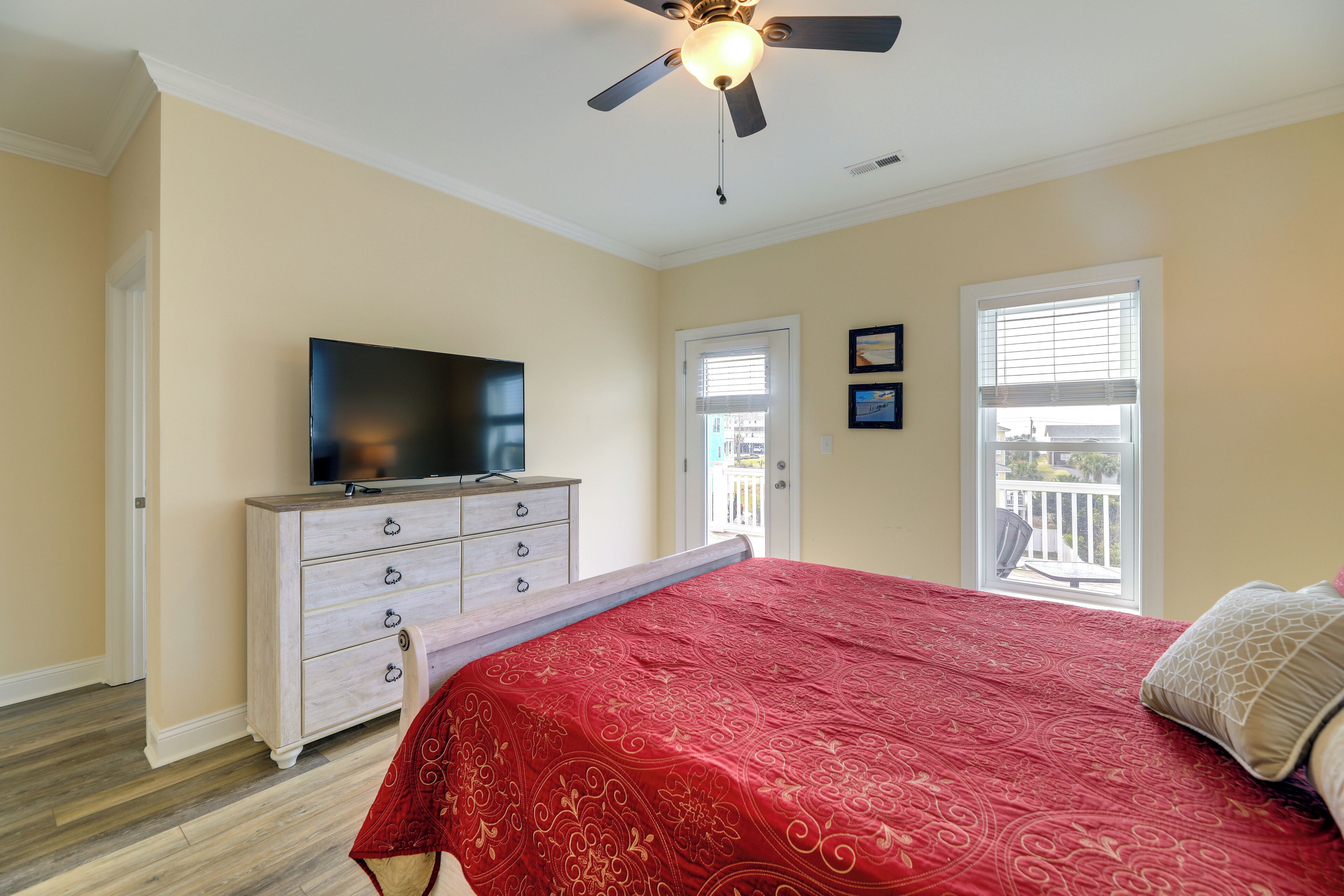 A bedroom with a bed, a dresser, a television, and a ceiling fan.