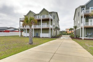 A two-story building with a balcony on the second floor, a covered front porch, and a concrete walkway leading to the entrance.