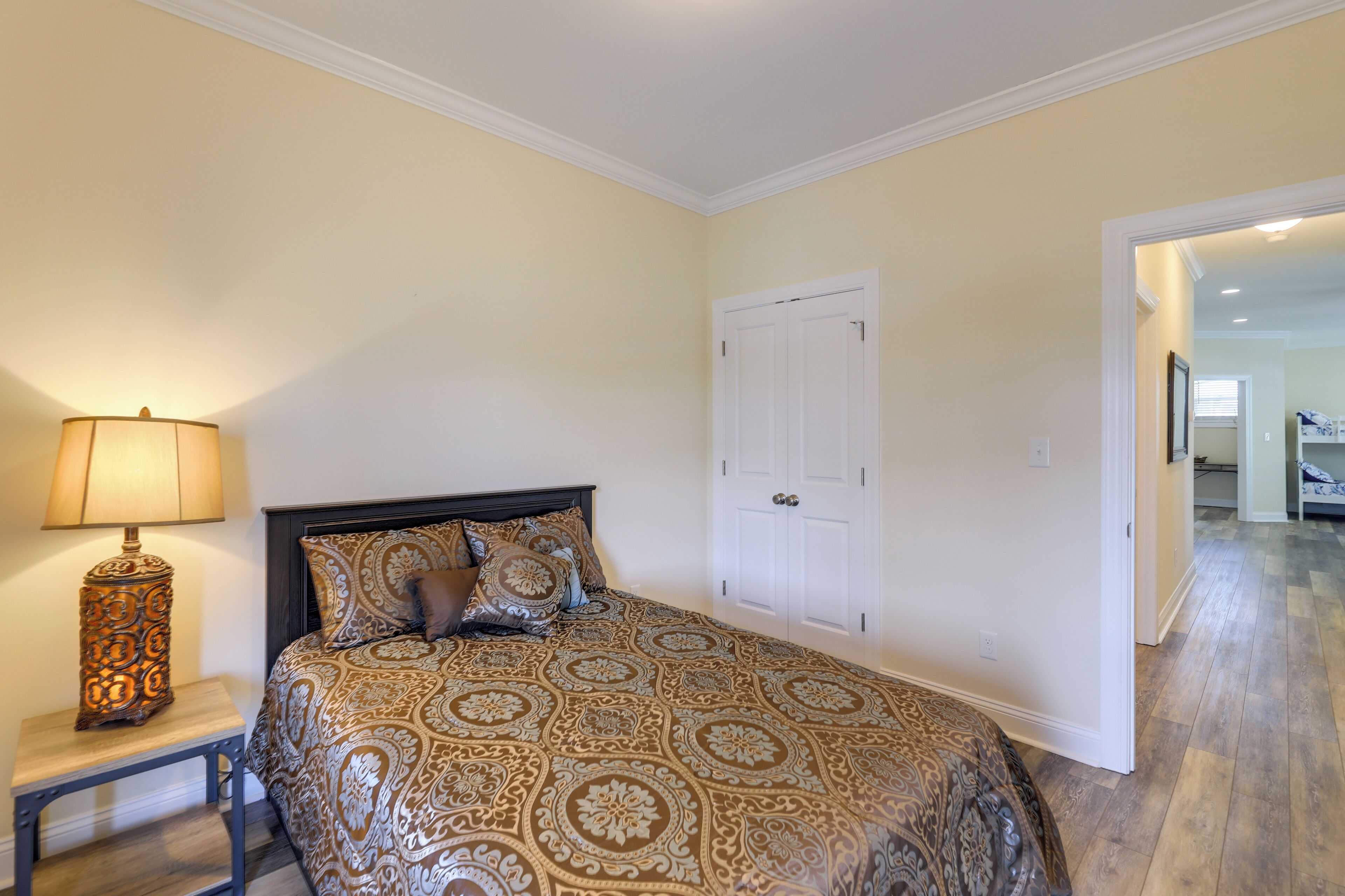 A bedroom with a bed, a nightstand, a lamp, and a white door.