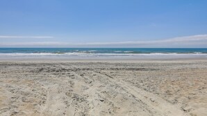Ein sandiger Strand mit Fußspuren, die zum Wasser führen.