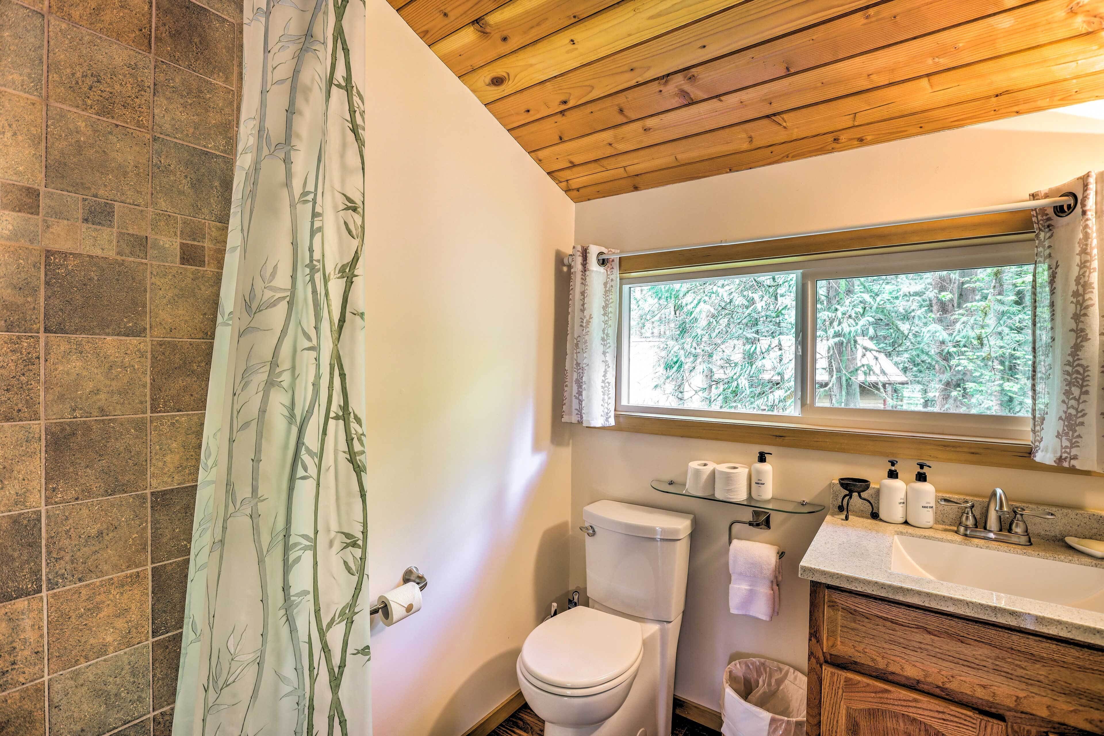 A bathroom with a toilet, sink, and window.