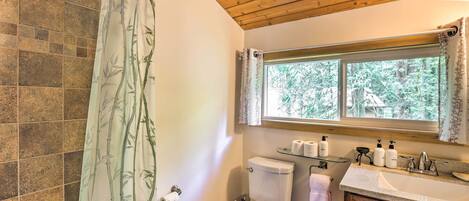 A bathroom with a toilet, sink, and window.