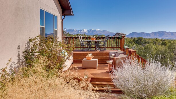 A deck with outdoor furniture, a view of mountains, and a building with large windows. - Scenic Mancos Hideaway < 2 Mi to Mesa Verde! (Mancos)