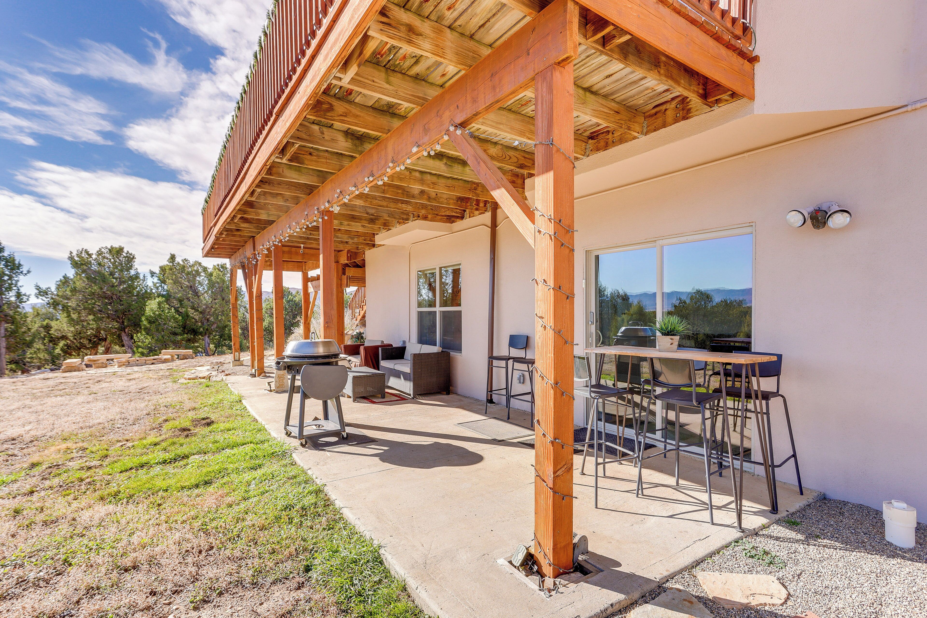 Une terrasse extérieure dotée d’une pergola en bois, d’un barbecue et d’un espace repas avec des chaises et des tables.