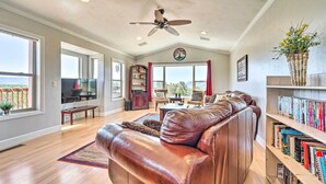 A spacious living room with a leather sofa, a ceiling fan, and a bookshelf filled with books. - Scenic Mancos Hideaway < 2 Mi to Mesa Verde! (Mancos)