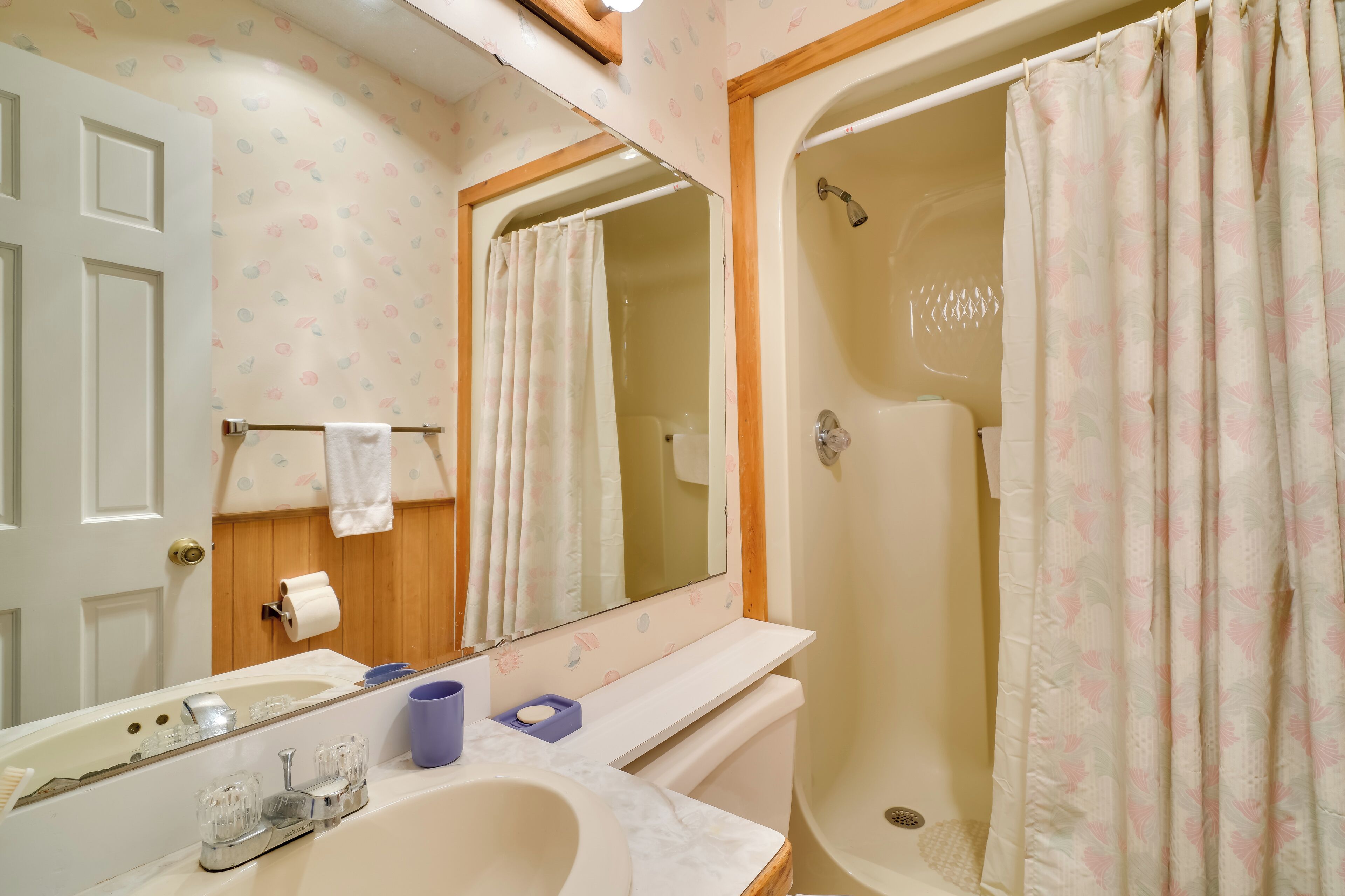 A bathroom with a sink, mirror, shower, and toilet.