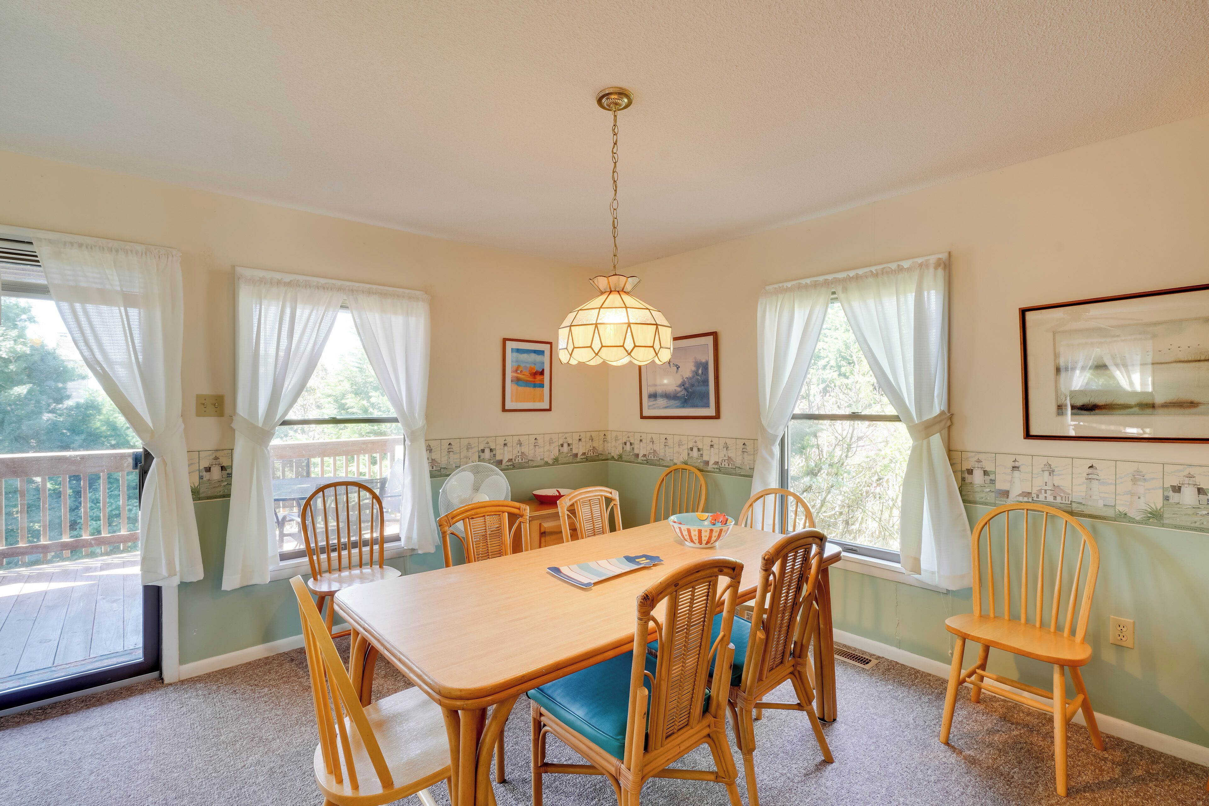 A dining area with a wooden table and chairs, a chandelier, and a view of the outdoors.