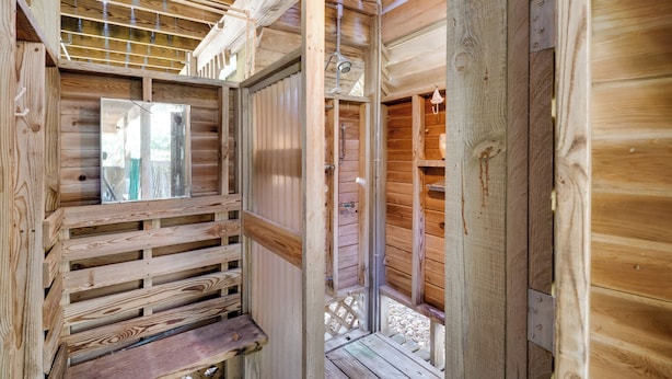 A wooden cabin interior with a wooden bench, a metal door, and a window. - Spacious Kill Devil Hills Getaway w/ 3 Decks! (Kill Devil Hills)