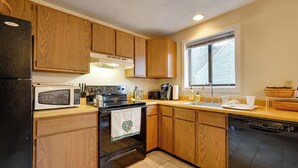 A kitchen with wooden cabinets, a microwave, an oven, a dishwasher, and a window providing natural light. - Dover Condo w/ Grill & Balcony: 3 Mi to Mt Snow! (West Dover)