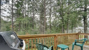 A wooden deck with a grill, two green plastic chairs, and a view of a forested area. - Dover Condo w/ Grill & Balcony: 3 Mi to Mt Snow! (West Dover)