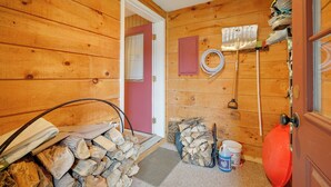 A wooden cabin interior with a door, a stack of firewood, a bucket, and a hose. - Dover Condo w/ Grill & Balcony: 3 Mi to Mt Snow! (West Dover)