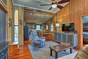 A spacious living area with a wooden ceiling, a ceiling fan, a television, and a dining area with wooden furniture. - Outer Banks Island Cottage - 1 Mi to Frisco Beach! (Frisco)