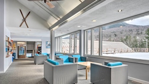 A spacious indoor area with wicker furniture, large windows, and a view of a mountainous landscape. - Lincoln Escape w/ Deck: 1 Mi to Loon Mountain! (Lincoln)