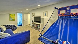 Ein Wohnzimmer mit einem blauen Sofa, einem Bücherregal, einem Fernseher und einer blauen Basketballkörbe.