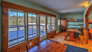 Une pièce spacieuse avec de grandes fenêtres, une terrasse en bois, une table à manger et un coin salon confortable.