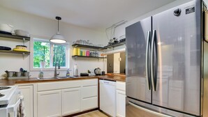 Una cocina moderna con armarios blancos, electrodomésticos de acero inoxidable y encimeras de madera.