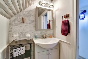 A bathroom with a white sink, a mirror, and a "HELLO LOVE" sign on a cabinet. - Peaceful + Chic Oasis: Fire Pit, Grill, Yard (Longview)