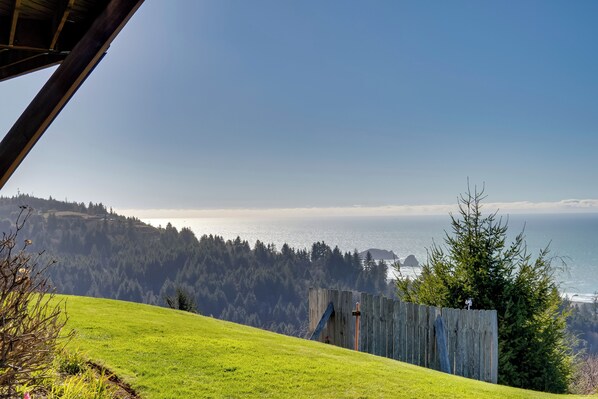 A grassy hillside with a wooden fence and a view of the ocean.
