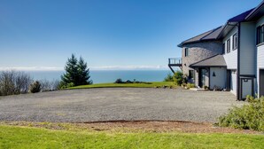 A modern house with a stone facade, a large driveway, and a view of the ocean. - Stunning 360 Ocean Views, Near Redwoods NP! (Smith River)