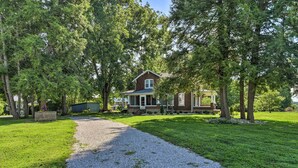 A house with a gravel driveway leading to a front porch, surrounded by trees and a well-maintained lawn. - Glasgow Home w/ Porch: Close to Lake & Caves! (Glasgow)