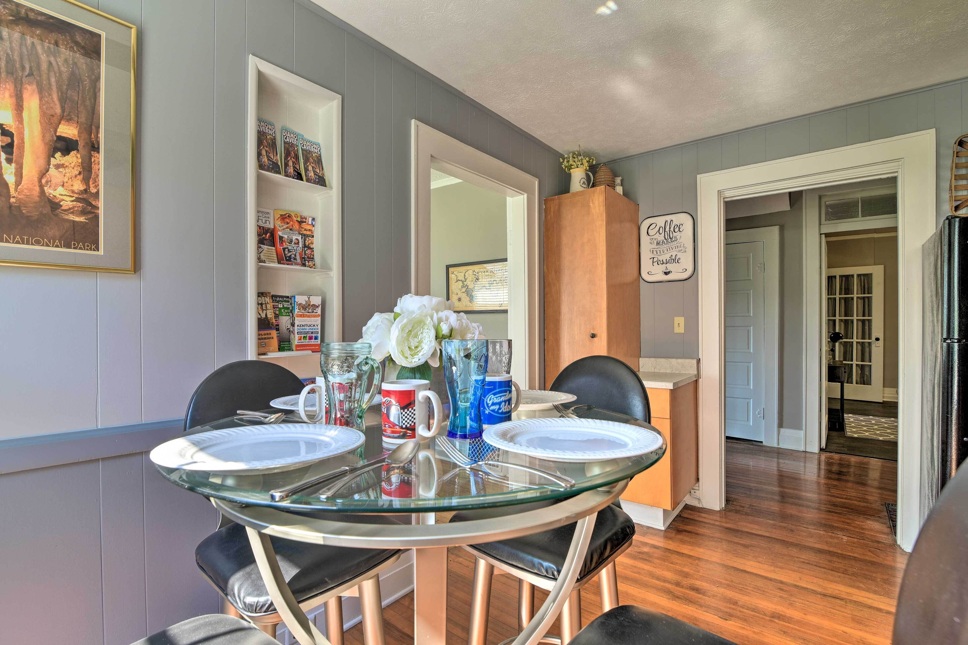 A dining area with a glass table, black chairs, and a white cabinet with books.