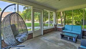 A covered patio with a hanging chair, a blue sofa, and a glass table. - Glasgow Home w/ Porch: Close to Lake & Caves! (Glasgow)