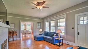 A spacious living room with hardwood floors, a sectional sofa, a blue leather ottoman, and a ceiling fan. - Glasgow Home w/ Porch: Close to Lake & Caves! (Glasgow)