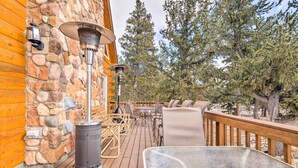 A wooden deck with stone walls, outdoor furniture, and a large metal table. - Deck & Dry Sauna! Fairplay 'high Creek Hideaway' (Fairplay)