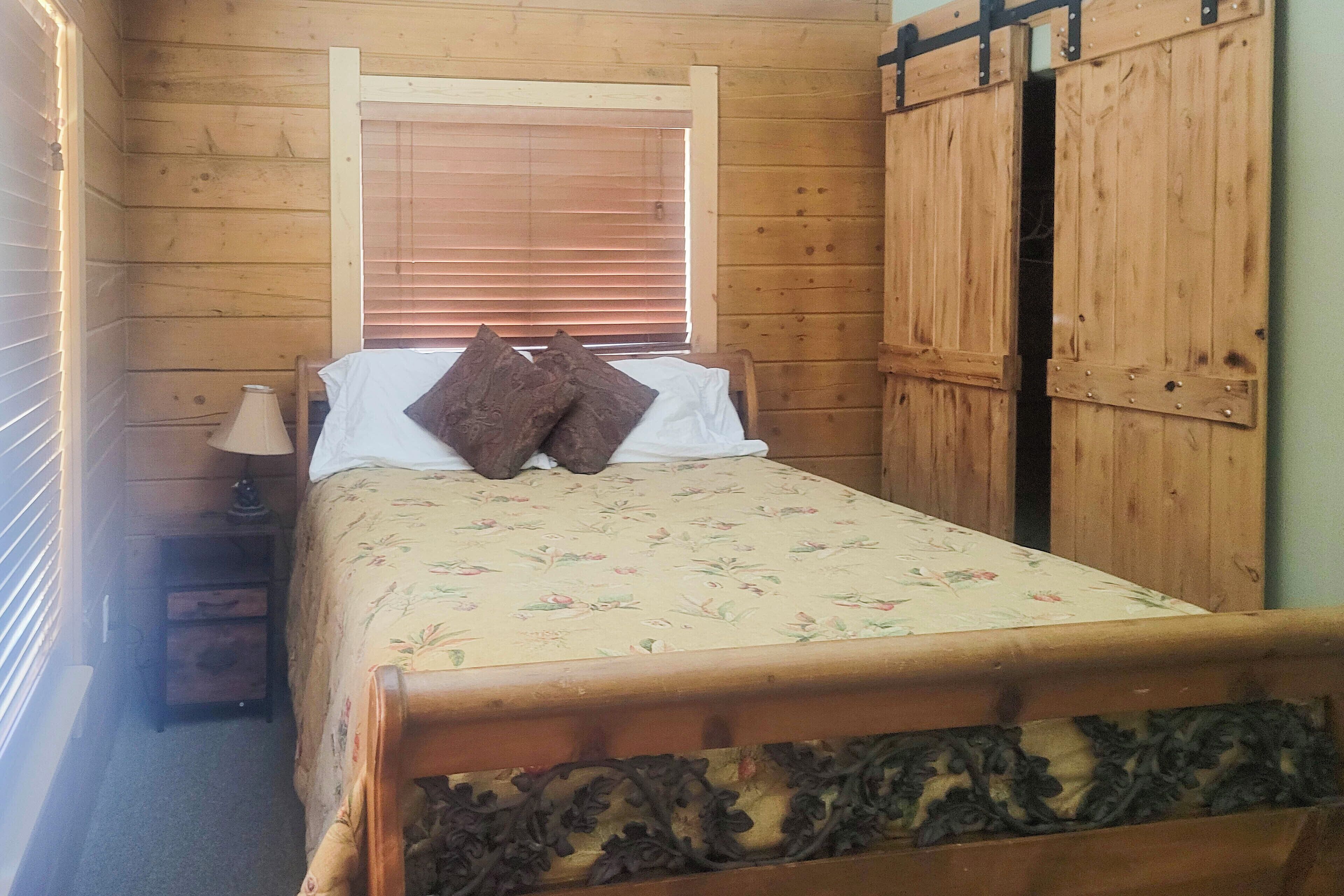 Une pièce en bois avec un lit, une fenêtre avec des stores et une armoire.