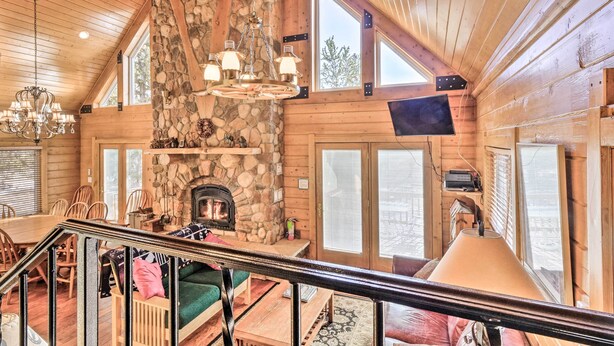 A log cabin interior with a stone fireplace, wooden walls, a dining area, and a staircase. - Deck & Dry Sauna! Fairplay 'high Creek Hideaway' (Fairplay)