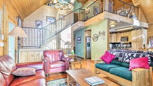 A spacious living area with a leather sofa, a green sofa with colorful cushions, a wooden coffee table, and a staircase leading to an upper level. - Deck & Dry Sauna! Fairplay 'high Creek Hideaway' (Fairplay)