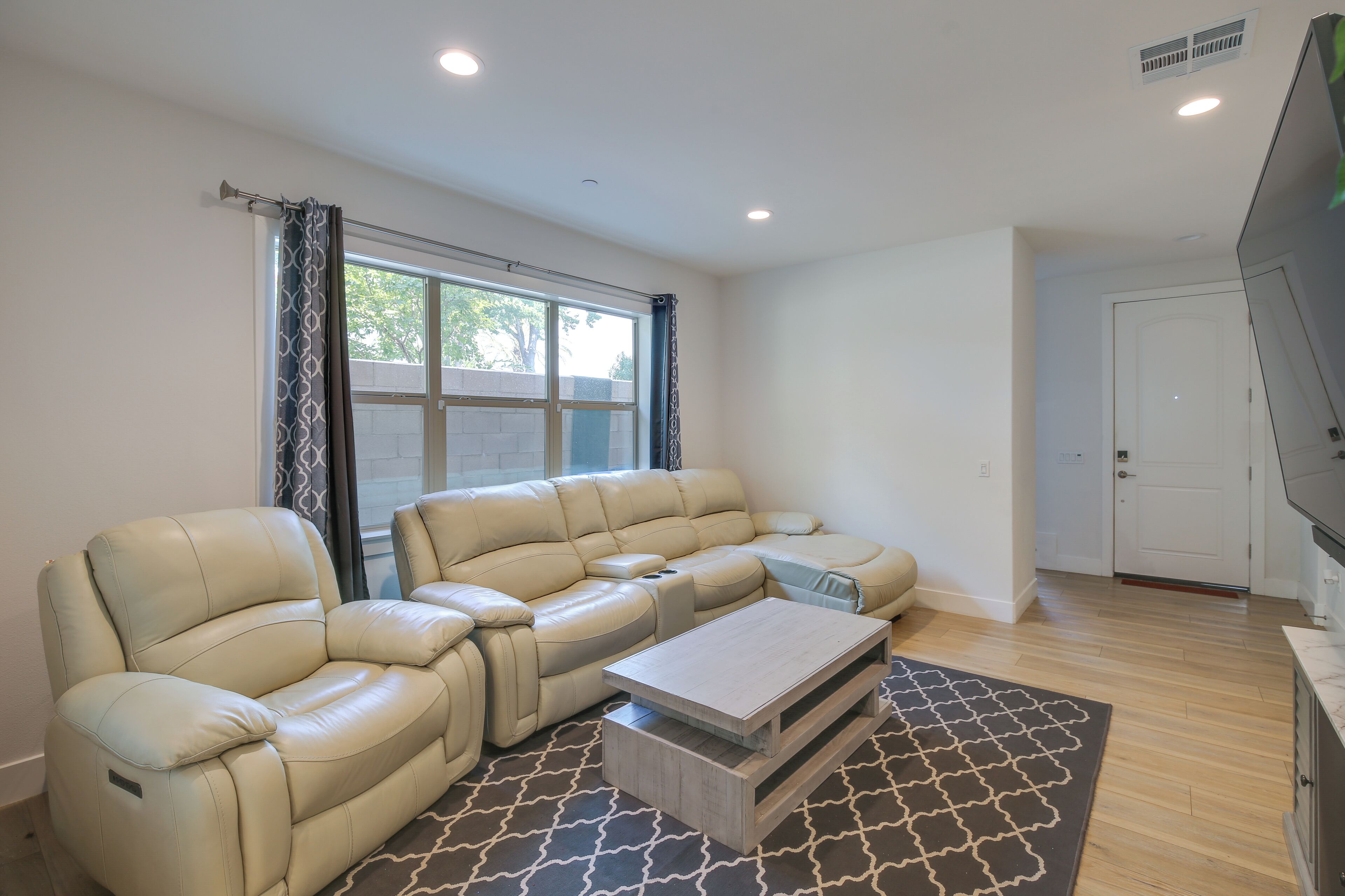 A modern living room with a sectional sofa, a wooden coffee table, and a patterned rug.