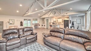 A spacious living area with leather sofas, a patterned rug, and a kitchen in the background. - Quaint, Cozy Outdoor Retreat Near Mt Rainier! (Roy)