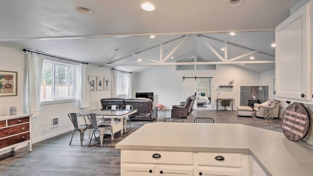 A spacious living area with a high ceiling, a central island, and a fireplace. - Quaint, Cozy Outdoor Retreat Near Mt Rainier! (Roy)