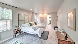 A bedroom with a large bed, a wooden nightstand, a dresser, and a mirror. - Quaint, Cozy Outdoor Retreat Near Mt Rainier! (Roy)