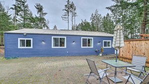A blue house with a paved patio, a table with chairs, and an umbrella. - Quaint, Cozy Outdoor Retreat Near Mt Rainier! (Roy)